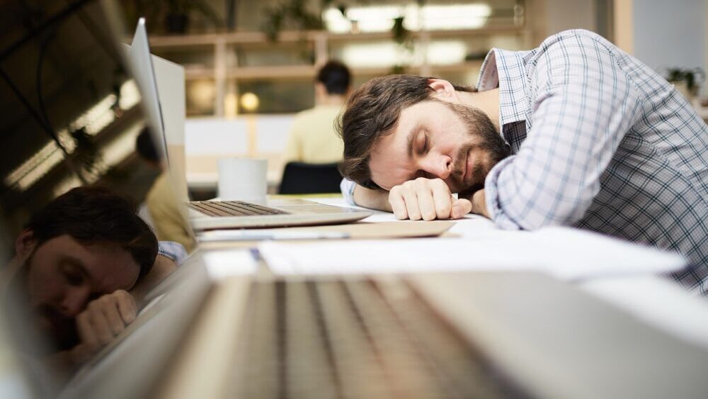 疲れてデスクに横たわる男性
